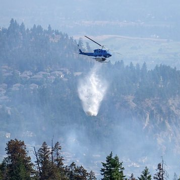 Water being dropped by helicopter on forest fire.